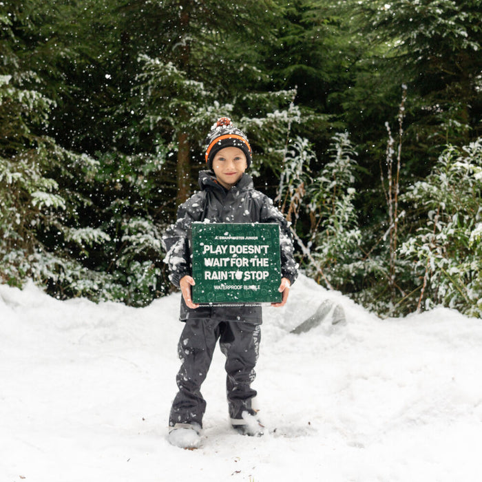 Child in snow holding a green box with text.